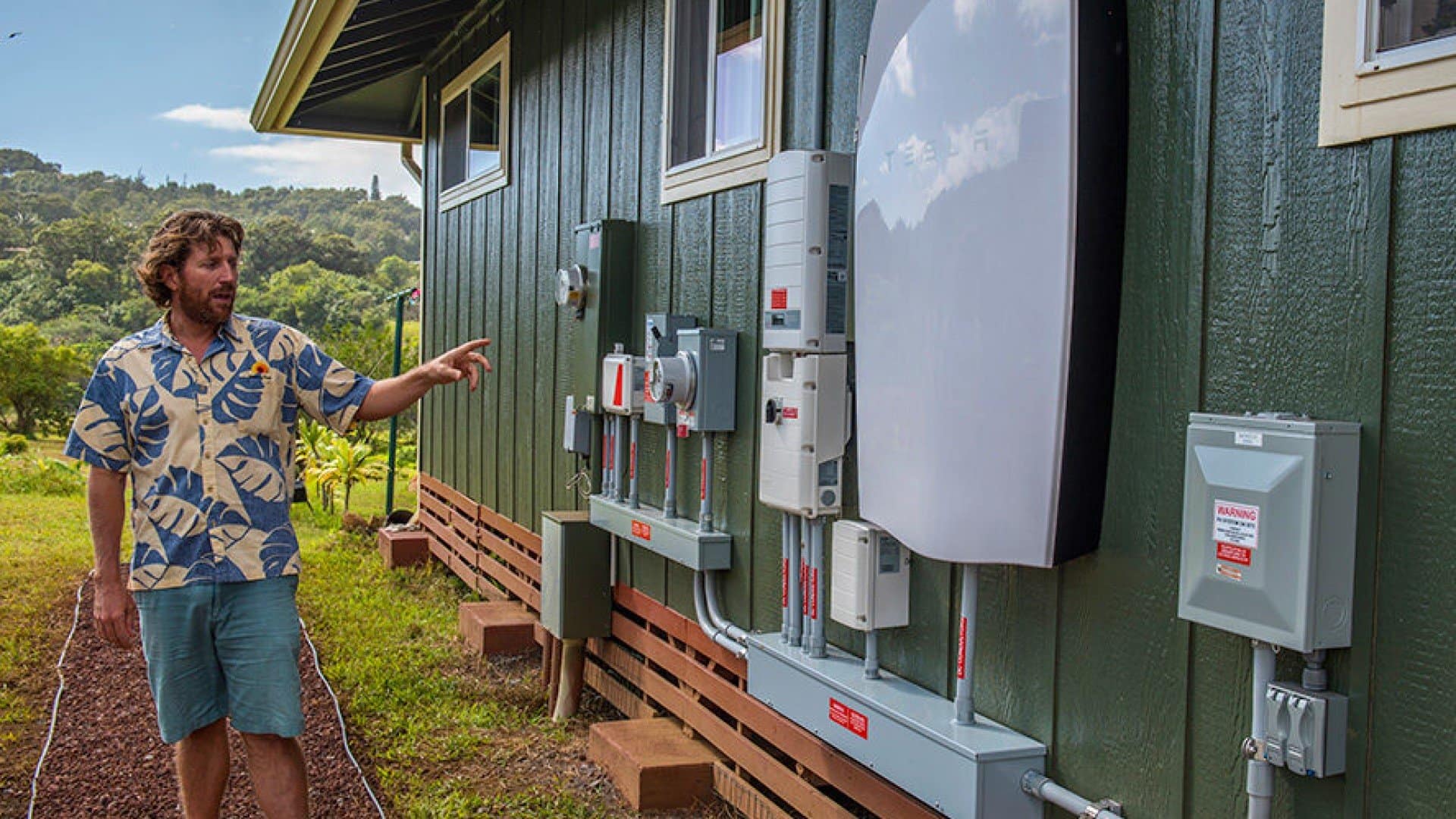 rising sun solar employee showcasing tesla powerwall installed on customer home