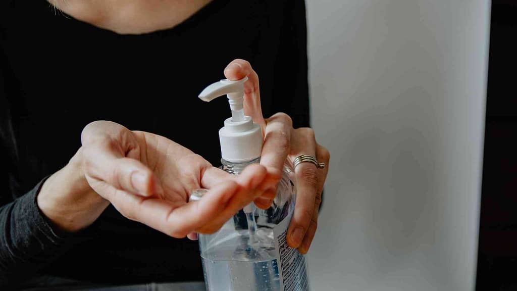 two hands holding and pumping sanitizer bottle