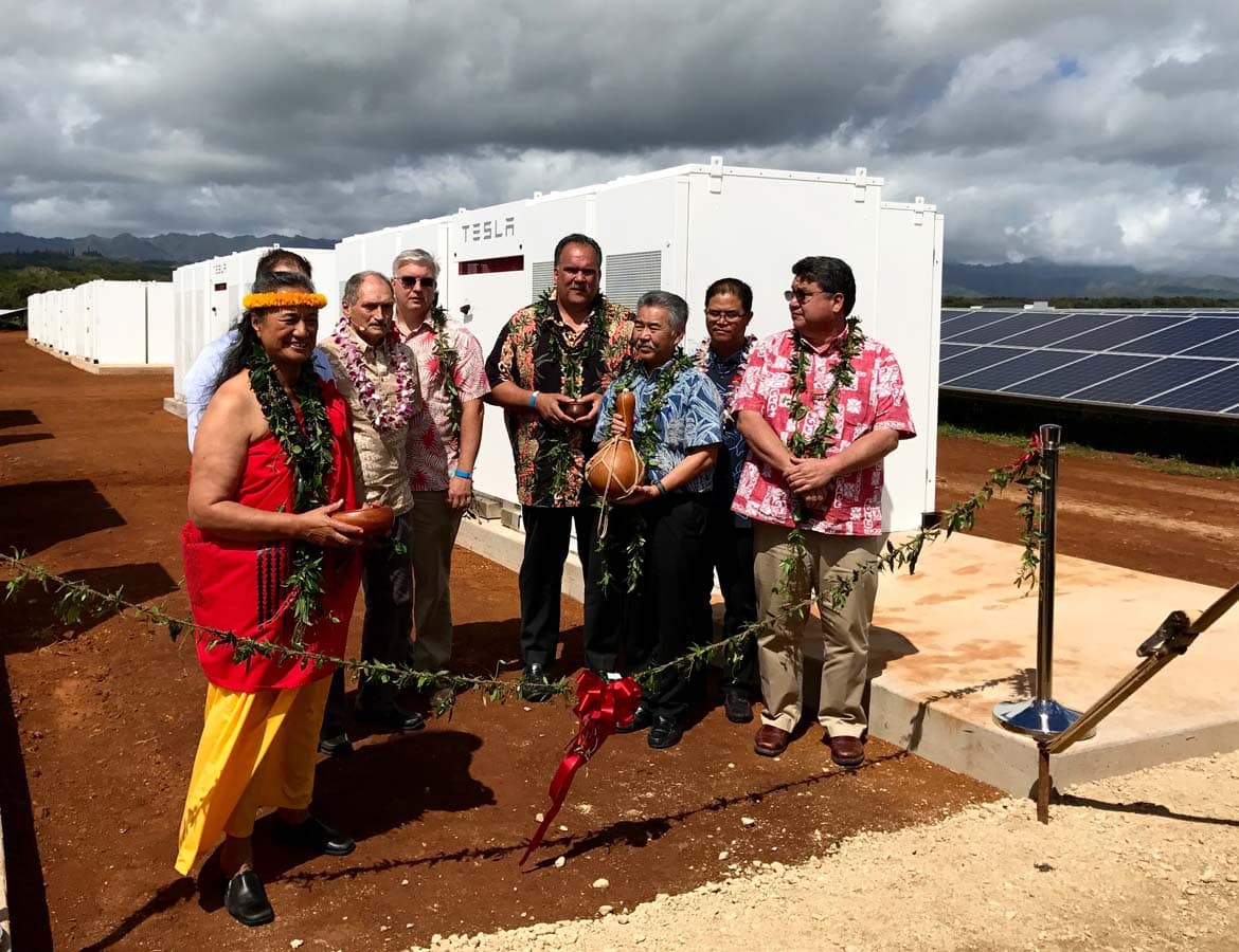 local hawaiians standing in front of tesla power storage during a traditional hawaiian blessing